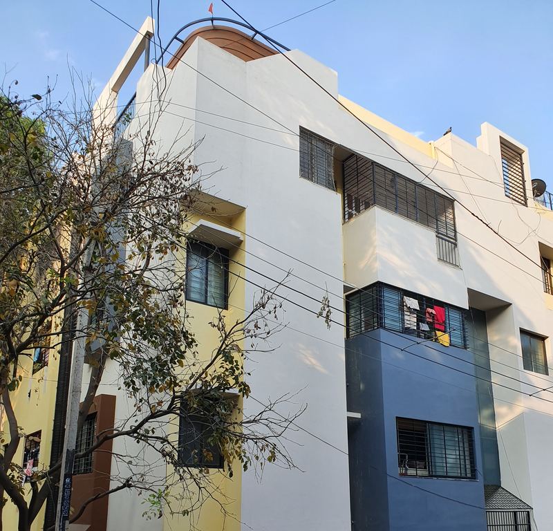 Completed white, yellow and blue apartment building on a Bangalore street corner