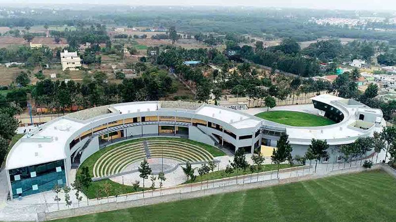 Aerial view of a curved campus building wrapped around a grass amphitheatre