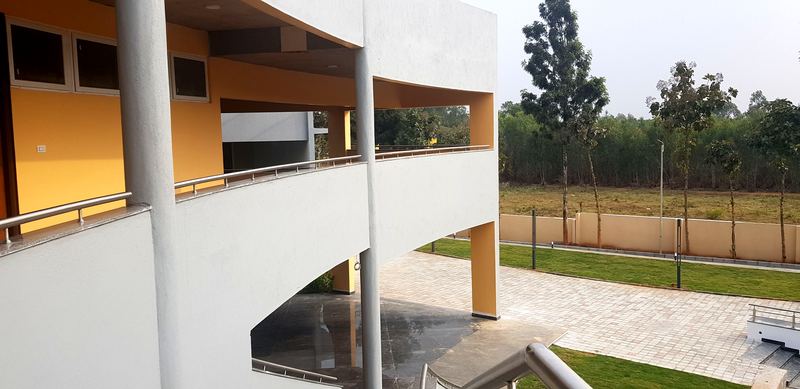 Curved balcony with yellow walls and round columns, looking out over the campus