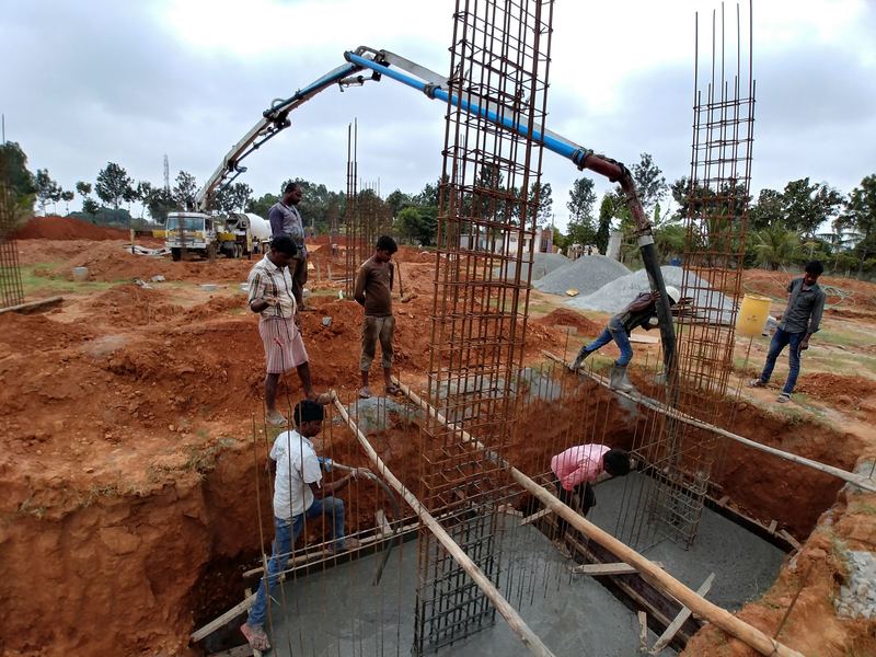 A boom pump placing concrete into a footing while the site team guides the pour