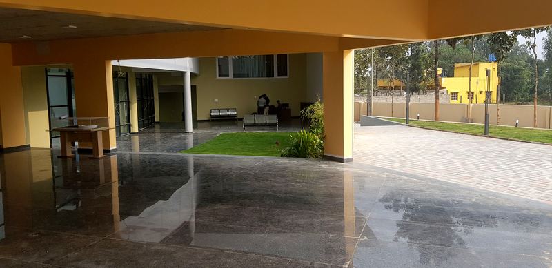 Open lobby with a polished stone floor, yellow columns and a lawn beyond