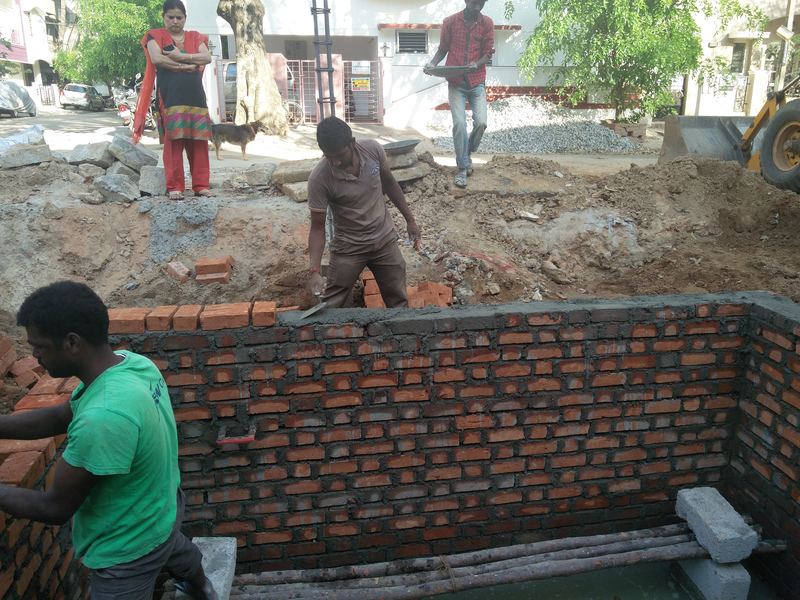Masons building a brick wall below ground level
